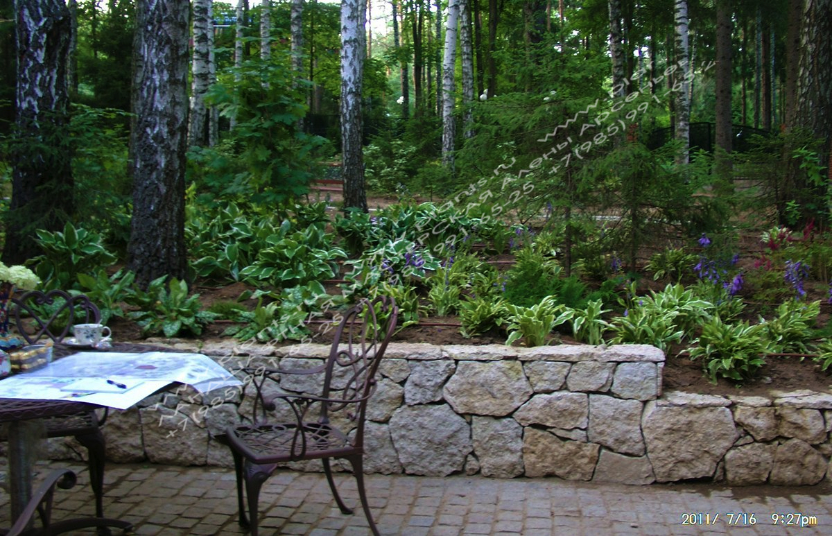 Подпорная стенка отделяет внутренний дворик от лесной части с многолетними цветами